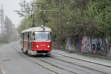 Fototapeta na wymiar Kyiv, Ukraine - April, 2020: Old red soviet tram in industrial area in cluody day.