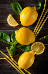 whole yellow juicy lemons, Basil, cocktail tubes on a dark wooden background, citrus, top view, flat lay