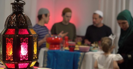 Authentic Muslims family around the table. Iftar is the evening meal with which Muslims end their daily Ramadan fast at sunset. They break their fast at the time of the call to prayer for the evening