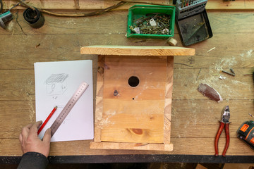 man makes by hands a wooden house for birds