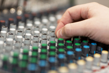 Hand of a male DJ on a sound mixer. Close-up.