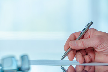 Man signs a document form with a ballpoint pen in the office