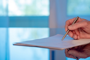 Man signs a document form with a ballpoint pen in the office