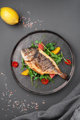 Hot grilled dorado fish with cherry tomatoes, arugula, lemon