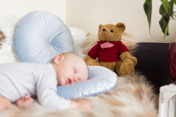 Little baby boy sleeping on a sofa on artificial fur, among toys - teddy bears 