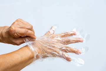 Senior woman's hands wearing disposable protective plastic gloves on grey background, Close up shot, Prevention from covid19, Coronavirus, Bacteria, Healthcare