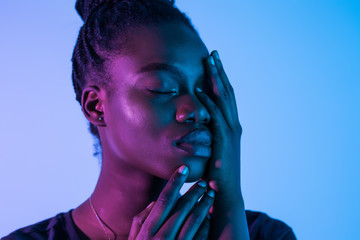 Young elegant african american woman in fashionable neon light background.
