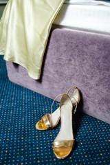 gold shoes on the background of a bed with a dress