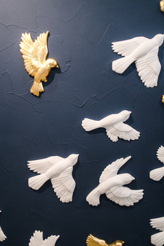 clay white and gold birds on the blue wall