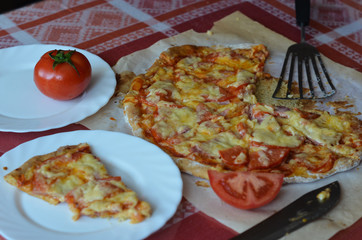 Homemade pizza, tomato, knife on a beautiful tablecloth