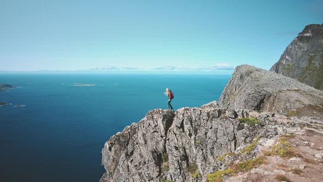 Woman traveler on mountain cliff edge alone travel hiking in Norway adventure active vacations healthy lifestyle backpacking landscape ocean aerial view