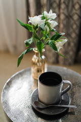 a mug of black coffee and fresh flowers on the tea table in the hotel room