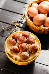 Composition of mashed potatoes with fried meatballs and eggs on dark background.