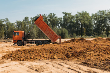 Fototapeta premium orange dump truck truck at a construction site transports sand