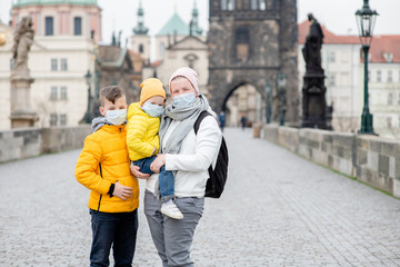 Woman with her children wearing  medical masks stand on empty Charles Bridge in Prague. Coronavirus...