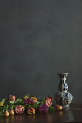 Delft blue vase with pink, yellow, red and purple tulips on wooden table.