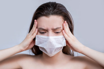 A terrified young woman in a medical mask stood against a gray background with blurred red virus molecules. The concept of coronavirus and avian flu panic. Rendered image