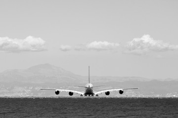 Fototapeta na wymiar Airplane On Runway By Sea Against Sky