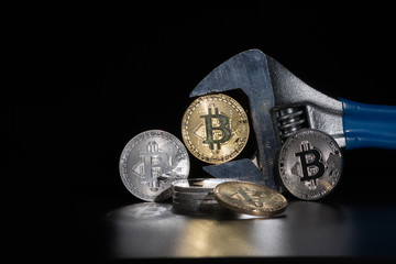 Bitcoin in wrench with reflection. Electronic money, cryptocurrency.