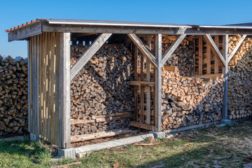 Holzlagerplatz: Gestapeltes Brennholz / Kaminholz (Holzwirtschaft) unter einem Schutzdach