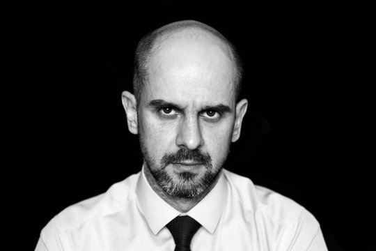 Black and white portrait of a bald man in a shirt and tie, heavy look, negative emotions, depression