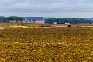 Fototapeta na wymiar Church in the village. Field in the foreground. Late autumn in Europe after harvesting.