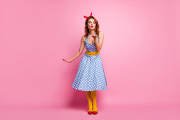 Full size photo of charming dreamy fancy girl send air kisses to rich wealthy guys wear red footwear polka-dot dress yellow pantyhose isolated over pink color background