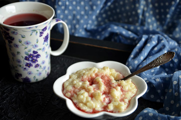 Rice on milk with raspberry juice. Tea in a mug in the background