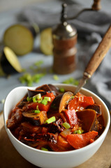 Eggplant stew with red peppers in a white bowl