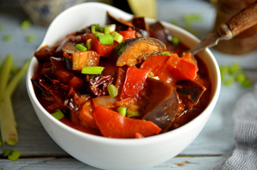 Eggplant stew in a white bowl on a wooden background