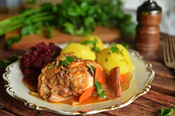 Braised rabbit meat on a plate with potatoes and grated beets