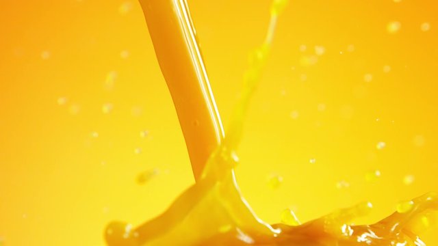 Super slow motion of pouring orange juice isolated on coloured background. Filmed on high speed cinema camera, 1000 fps.