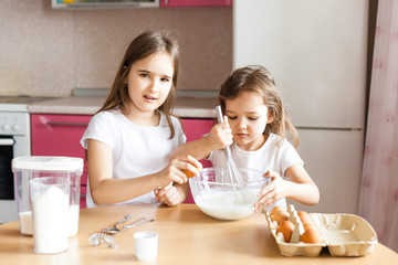 Obraz na płótnie Canvas Sisters prepare Breakfast, pastries, mix flour, milk, eggs, pancakes in a bowl, children help mother, family Breakfast, cooking