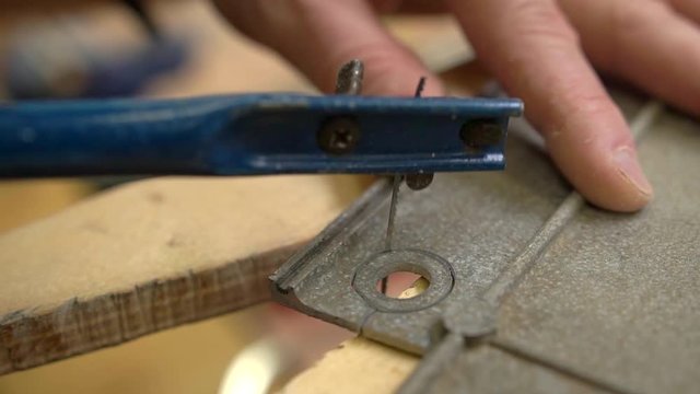 person hands cut aluminium circle with blue fretsaw crafting vintage jetliner model in workshop extreme close view