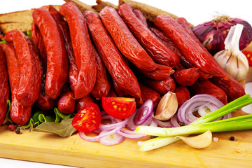 
sausage on a cutting board with herbs and vegetables white background