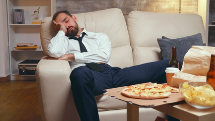 Overworked businessman sleeping on the couch