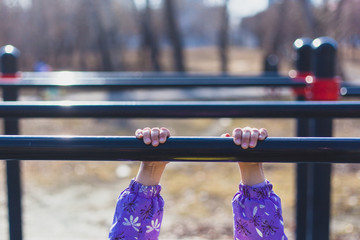 The girl is engaged in street turnstiles, body exercise, hand development, physical exercises, yoga, stretching, joy of communication, walking, spring