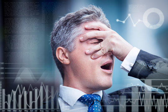 Close-up of face of confused middle aged Caucasian businessman covering face with hand. Desperate business man with virtual statistical charts