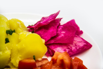 Boiled potatoes, tomatoes and pickled cabbage name Pelyustka on white plate. Healthy breakfast with boiled potatoes, tomatoes and red pickled cabbage. Delicious and diet meal for lunch without GMO