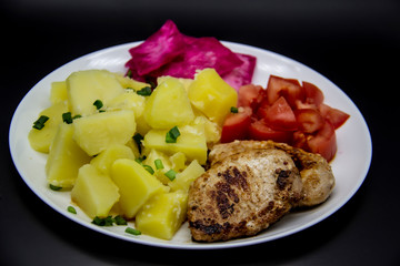 Mini steaks of meat with potatoes, tomatoes and pickled cabbage name Pelyustka on white plate. Healthy breakfast with meat, boiled potatoes, tomatoes and red pickled cabbage. Delicious meal for lunch