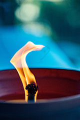 Close-up of big flame of a burning candle with blue background