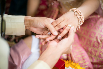 groom wears ring on bride's finger in wedding ceremony
