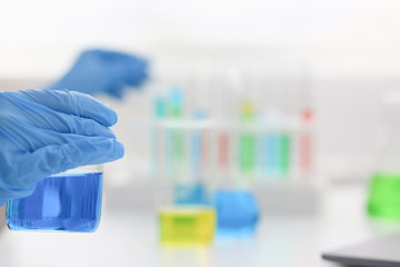 Female chemist holds test tube of glass in his hand overflows a liquid solution of potassium permanganate conducts an analysis reaction takes various versions of reagents using chemical manufacturing.