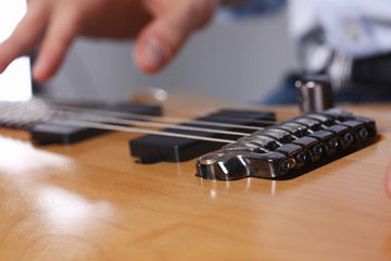 Male arms holding and playing classic shape wooden electric guitar closeup. Six stringed learning...