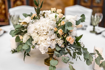 The bride's bouquet of white and yellow flowers on wedding arrangement in restaurant. Beautiful bridal bouquet of white and yellow peonies and roses on the table in the restaurant