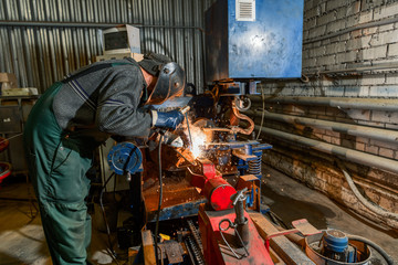 A welder is welding metal parts. - obrazy, fototapety, plakaty