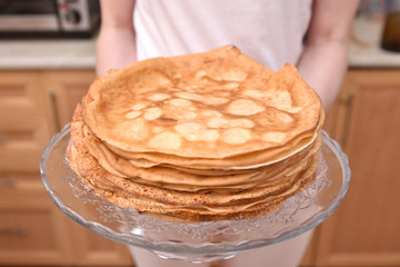Young woman housewife holds a lot of pancakes. Quarantine household chores concept