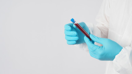 Male model with PPE suite and Hand with glove is holding blood collection tube on white background.