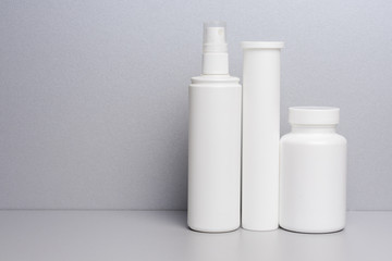 photo of three plastic cans for package pills and vitamins  for protection against coronavirus KOVID-19 on a grey background. photo without bottle labels