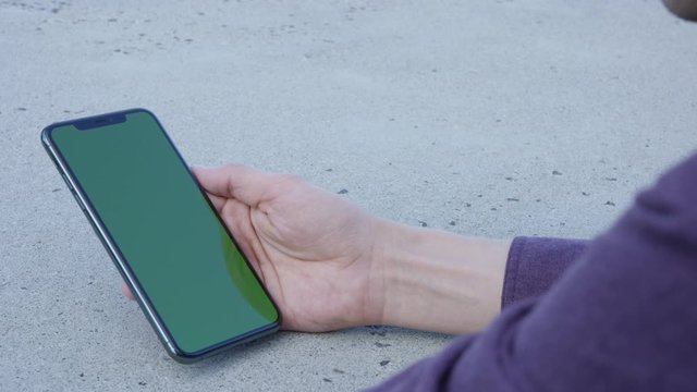 Hand holding modern smartphone taps and swipes up with green screen chroma key